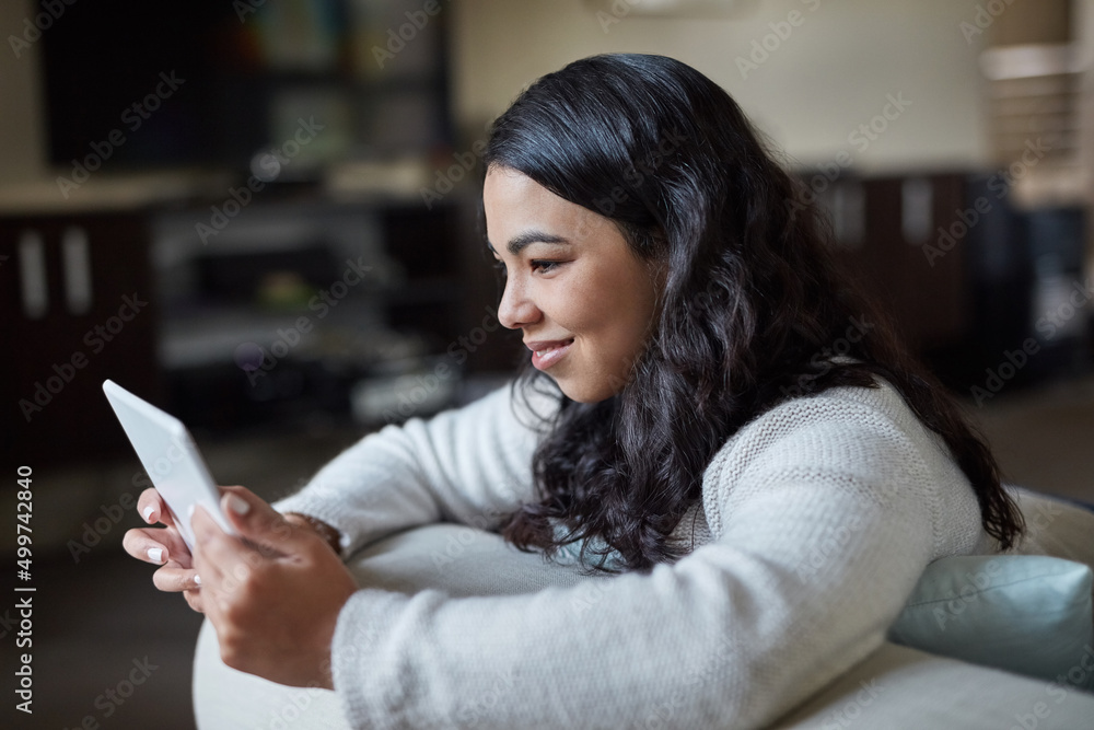 Updating all her favourite apps. Shot of an attractive young woman using a digital tablet at home.