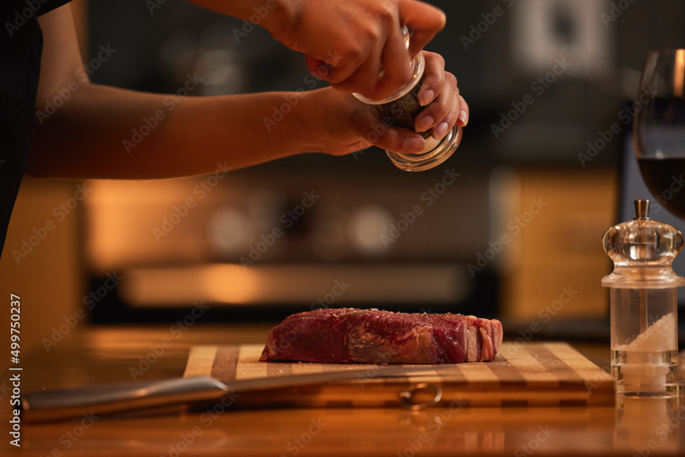 Meat should always be well seasoned. Shot of a woman seasoning a piece of steak for dinner.