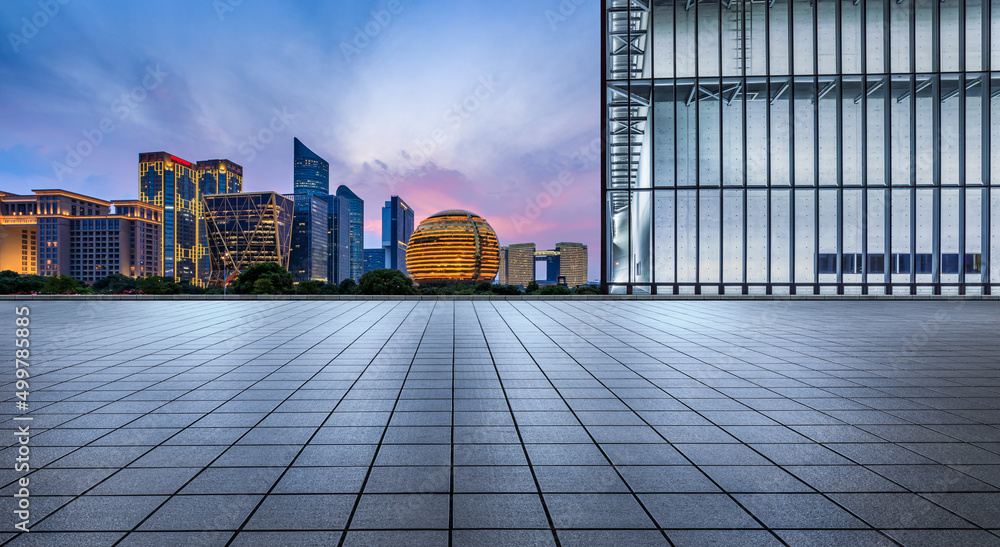 Empty square floor and city skyline with modern commercial buildings in Hangzhou at night, China.