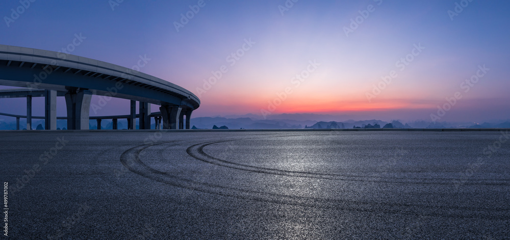 日出时天空乌云密布的柏油路和山