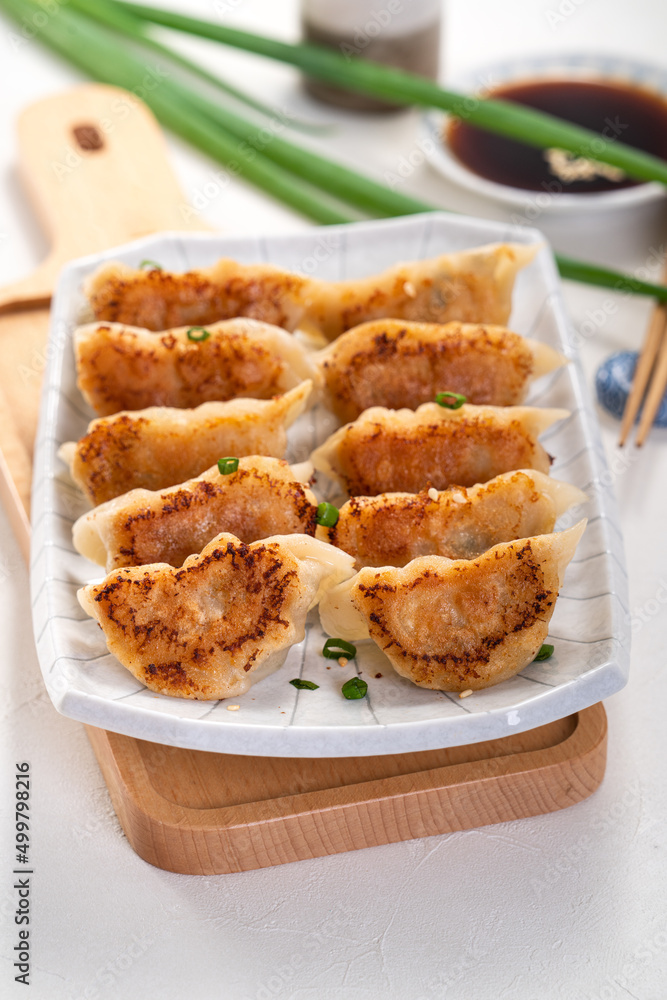 用酱油在白色桌子背景上的盘子里煎饺子饺子饺子。