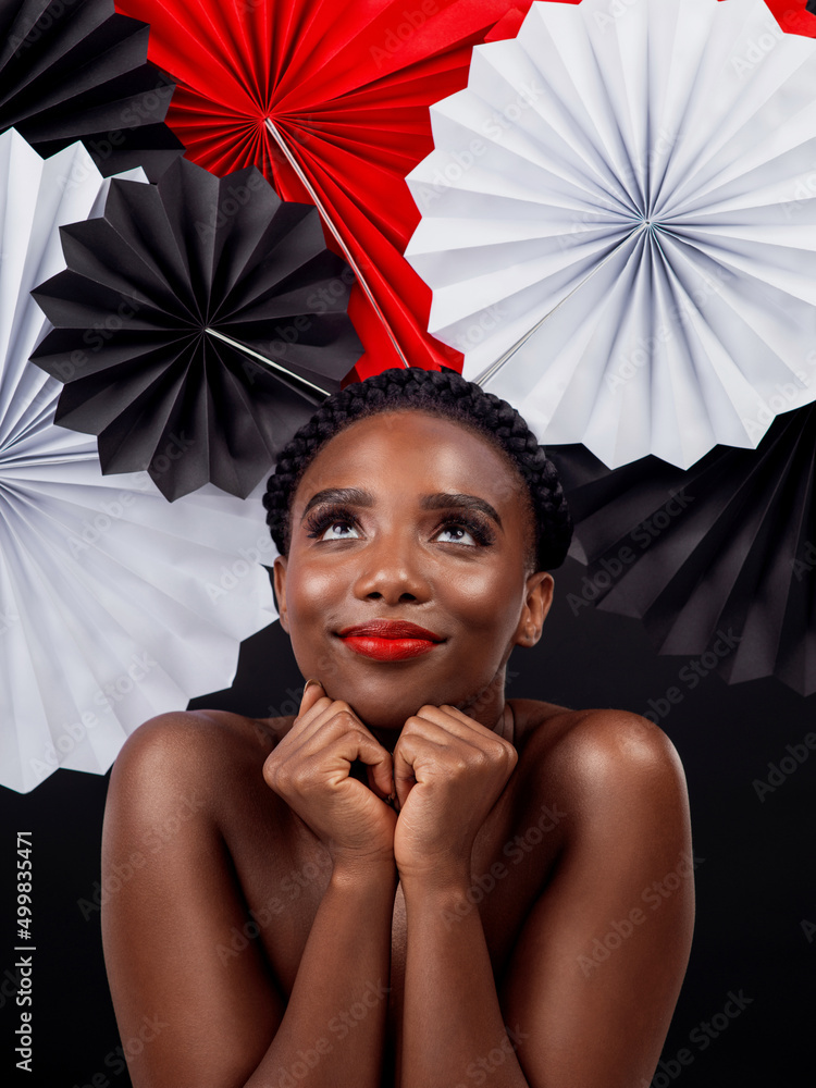 Her style is an ode to Japan. Studio shot of a beautiful young woman posing with a origami fans agai