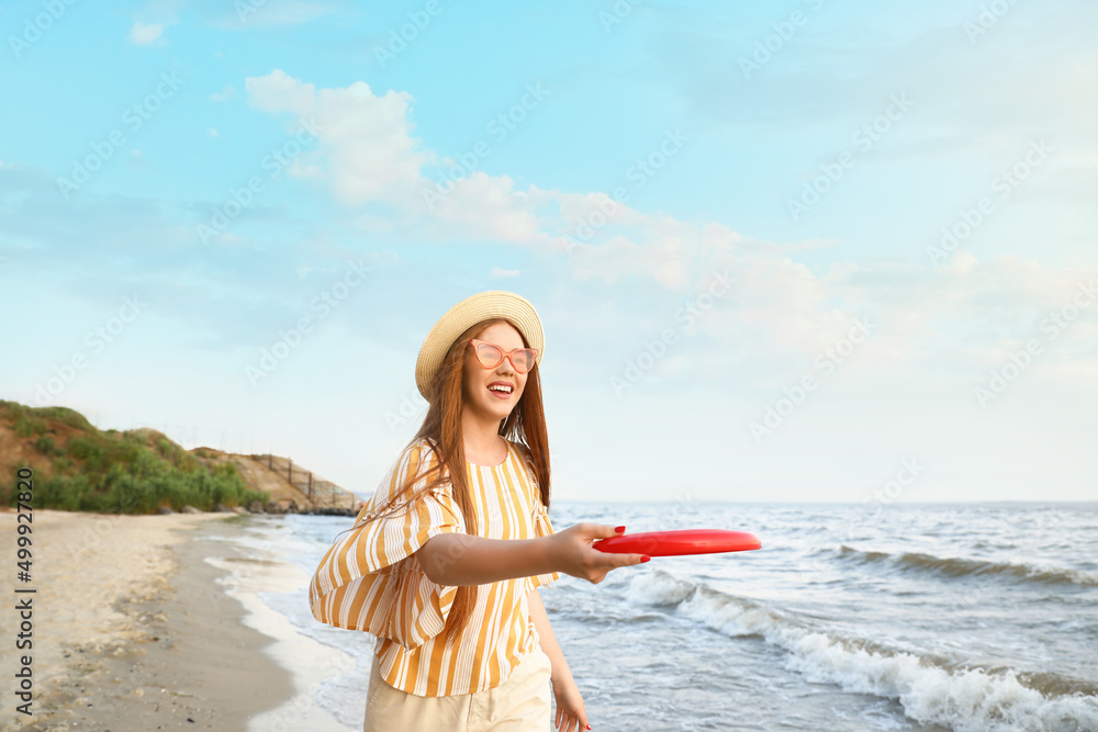 快乐的年轻女子在海边玩飞盘