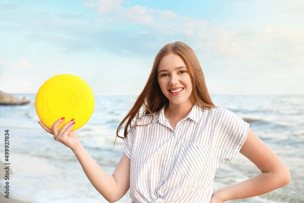 Happy young woman with frisbee on sea beach