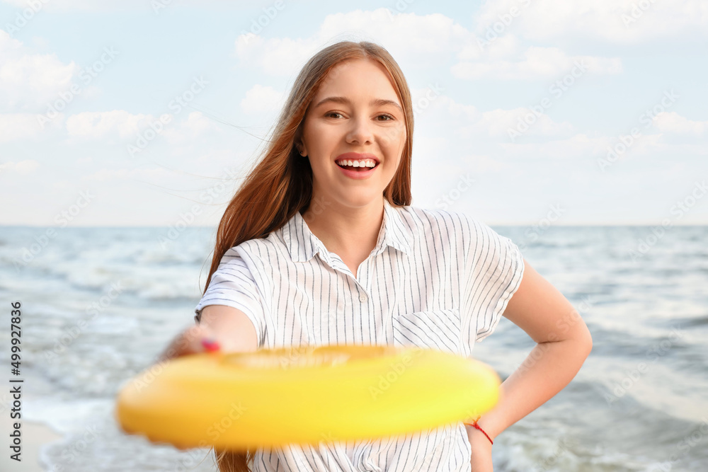 快乐的年轻女子在海边玩飞盘