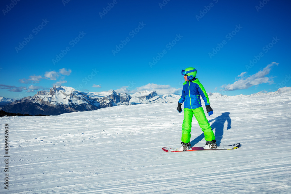 Child go downhill on snowboard over tops of mountain