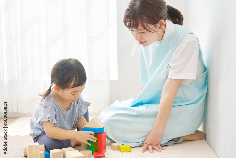 積み木で遊ぶ保育士と女の子