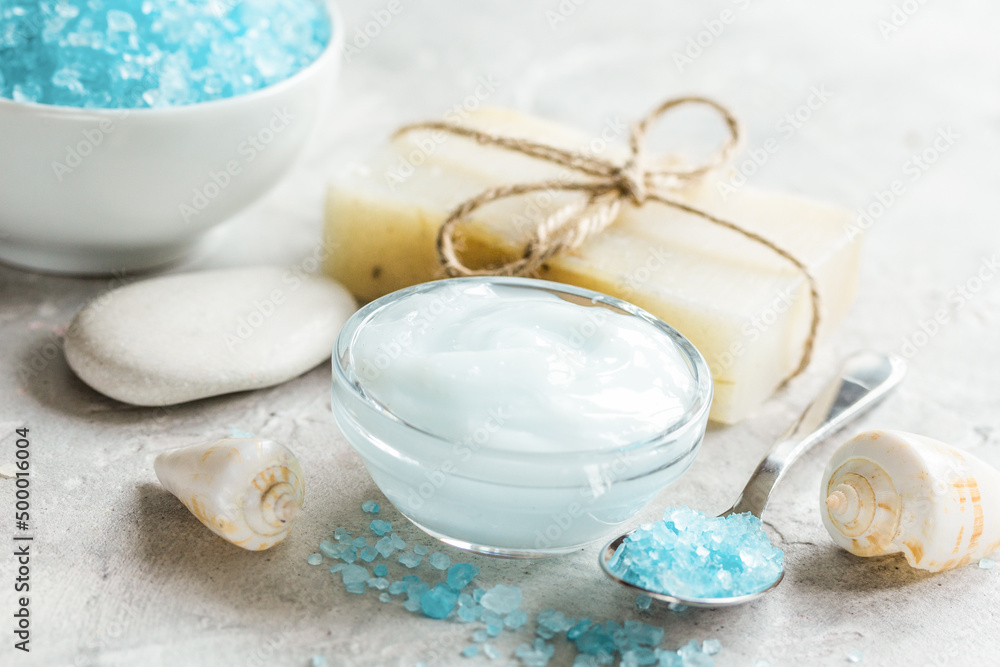 Home cosmetic with cream and blue sea salt on stone background