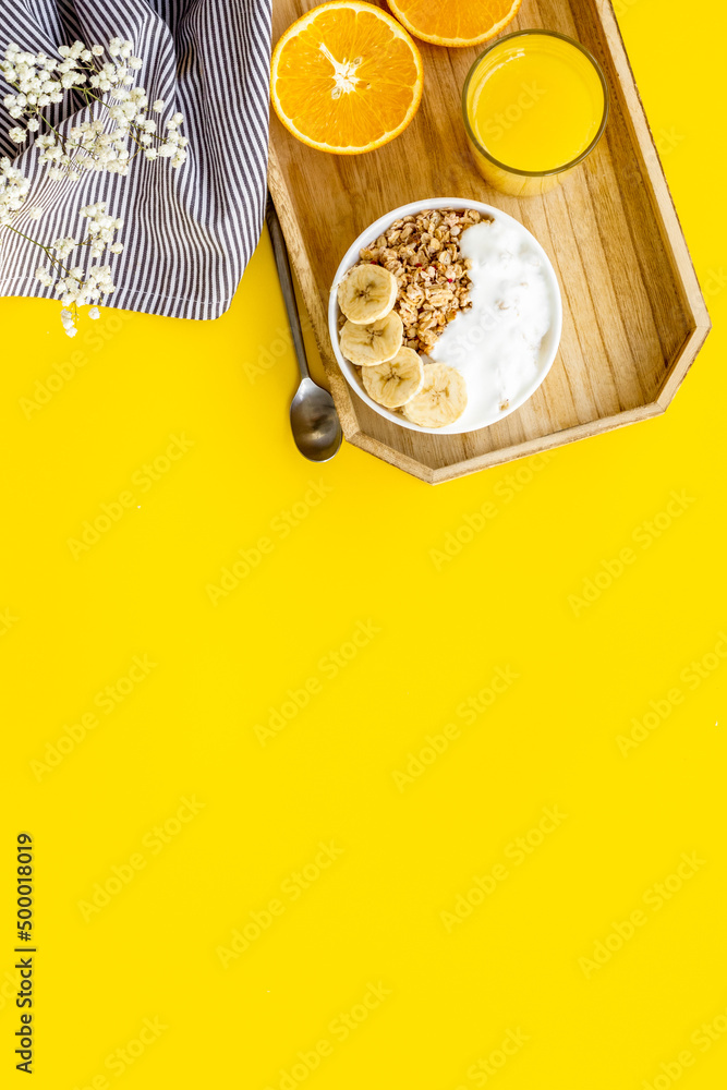 Bright breakfast with granola and orange juice on yellow background top view mockup