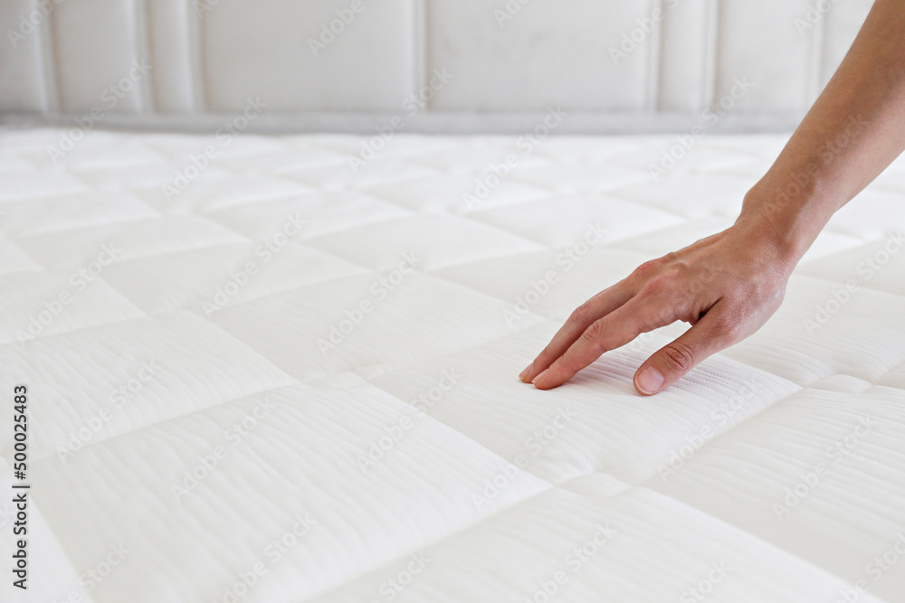 Cropped shot of young womans hand testing white orthopedic matress on firmness. Female pressing hyp