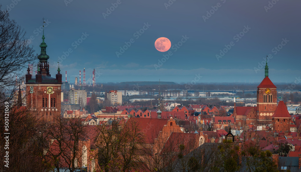 A full moon rising over the city of Gdansk at dusk. Poland