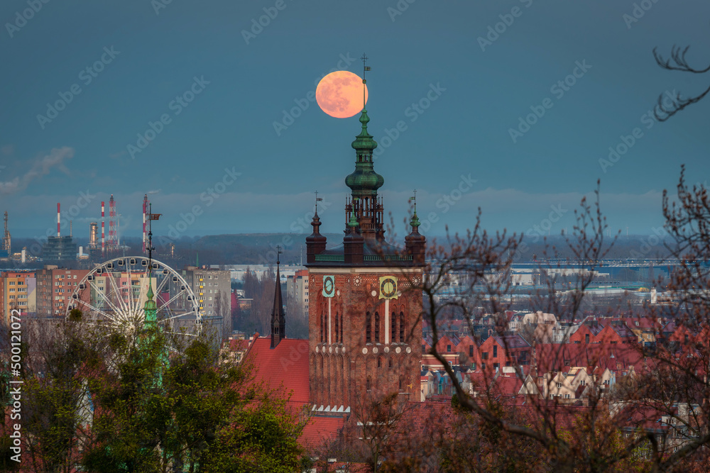 A full moon rising over the city of Gdansk at dusk. Poland