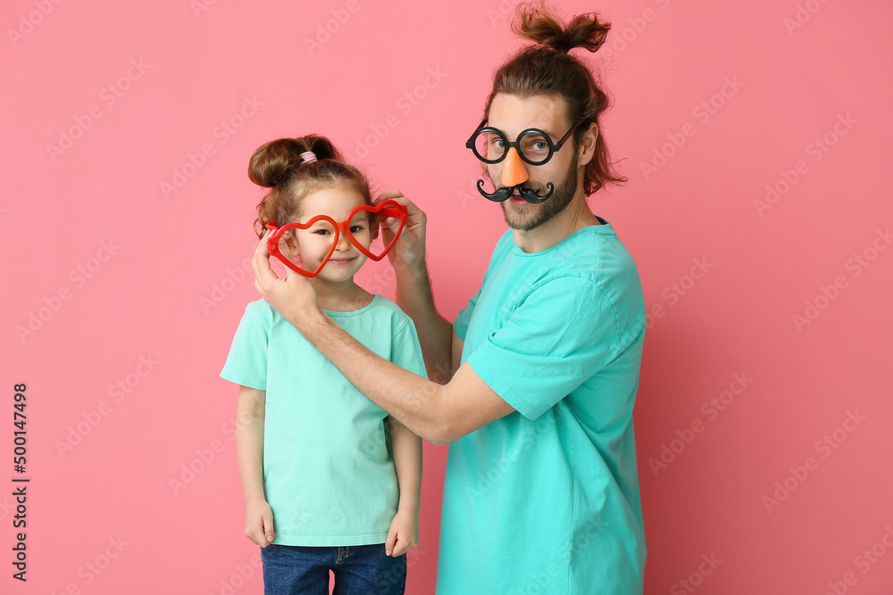 Funny man and her little daughter in disguise on pink background. April fools day celebration