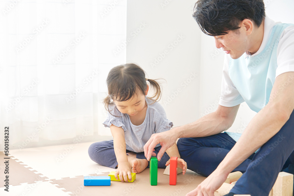 積み木で遊ぶ保育士と女の子