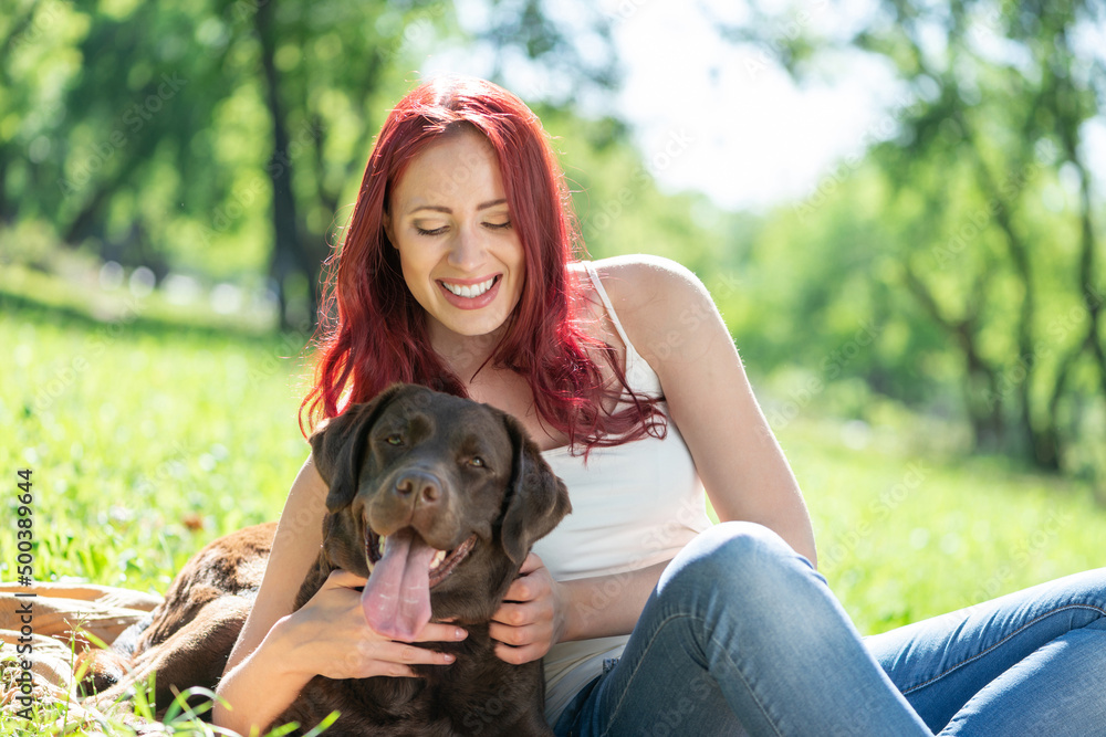 Young attractive woman hugs her dog in the park.