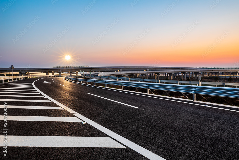 空旷的柏油公路和街灯，日落时天空美丽