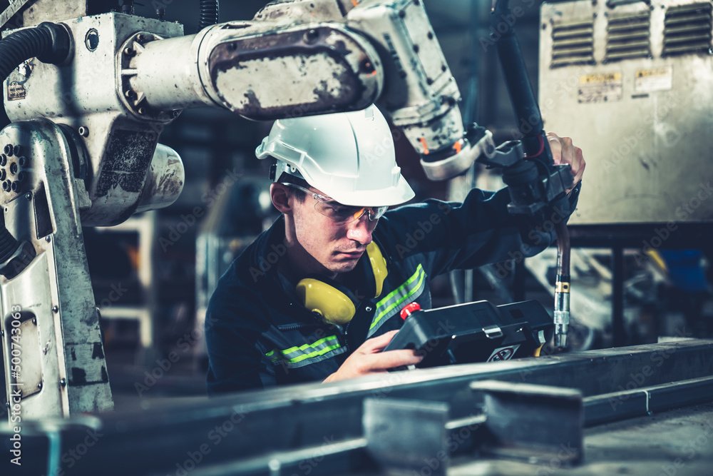 Young factory worker working with adept robotic arm in a workshop . Industry robot programming softw