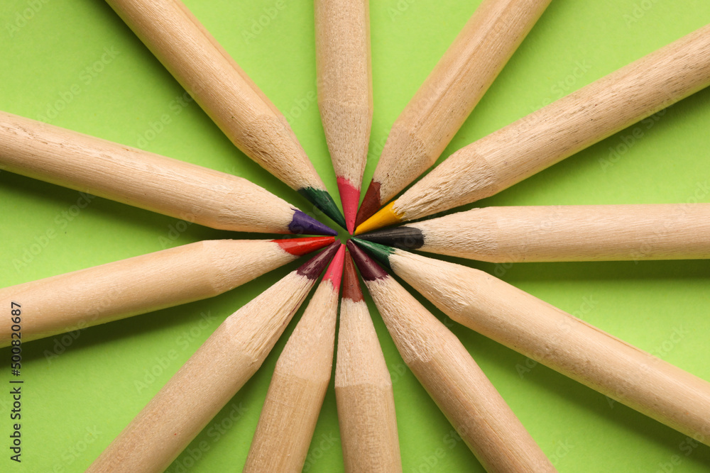 Colorful pencils on green background