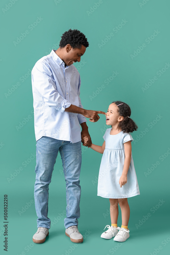 Portrait of little African-American girl and her father on green background