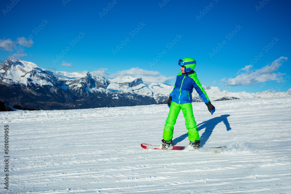 带背景的阿尔卑斯山坡上的男孩滑雪板滑梯