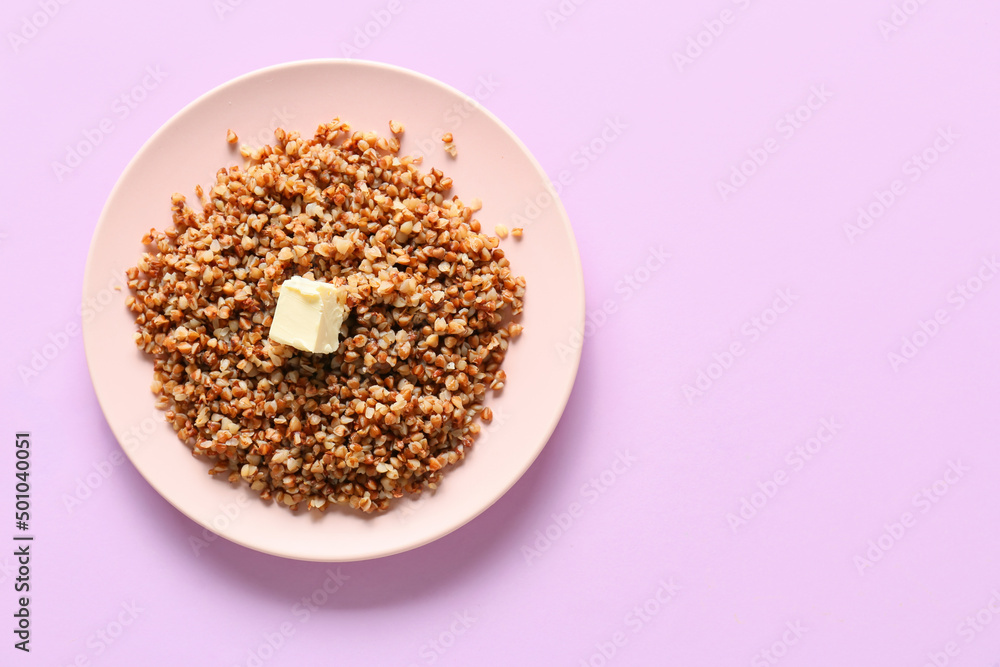 Plate of tasty buckwheat porridge on pink background