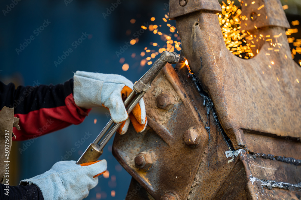 Industrial worker metal cutting with acetylene torch at factory welding steel structure, Welder is w