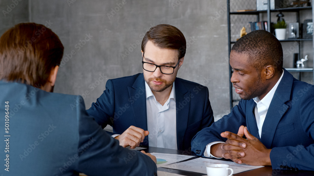 Young people in suits discussing problems in business in a loft