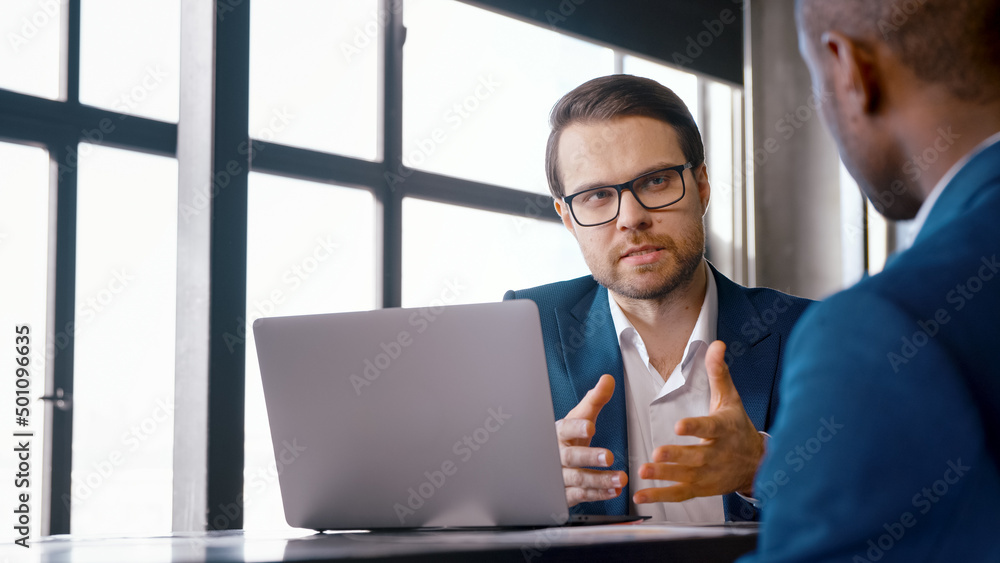 Young professional in a suit interviewing an African American man at a desk