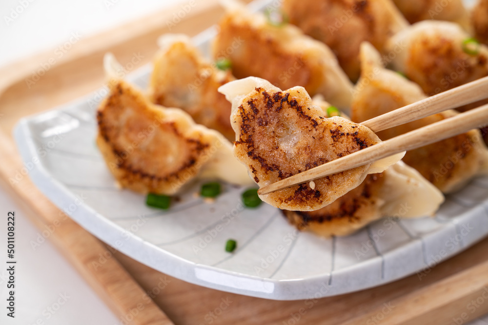 白桌子背景上放着酱油的锅里煎饺子饺子饺子。