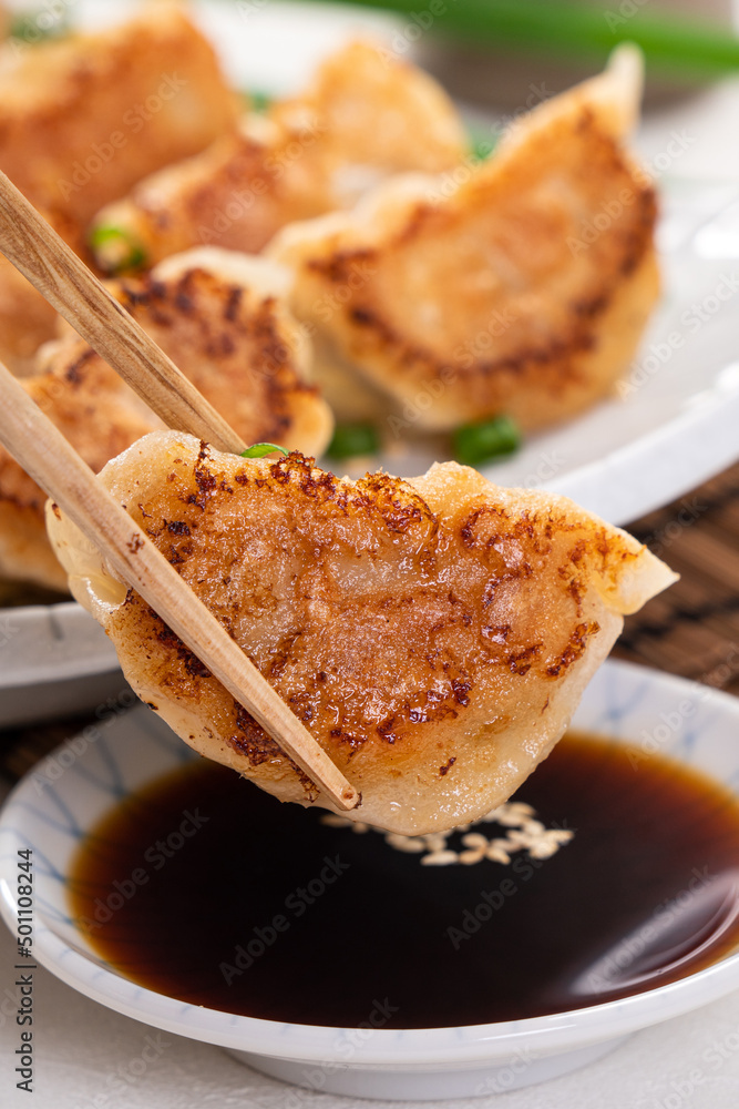 白桌子背景上放着酱油的锅里煎饺子饺子饺子。