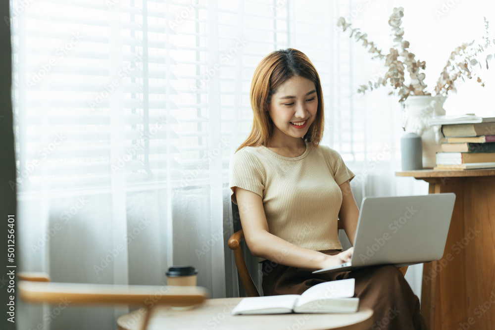 亚洲年轻女性在咖啡馆用笔记本电脑和财务报告工作的肖像。