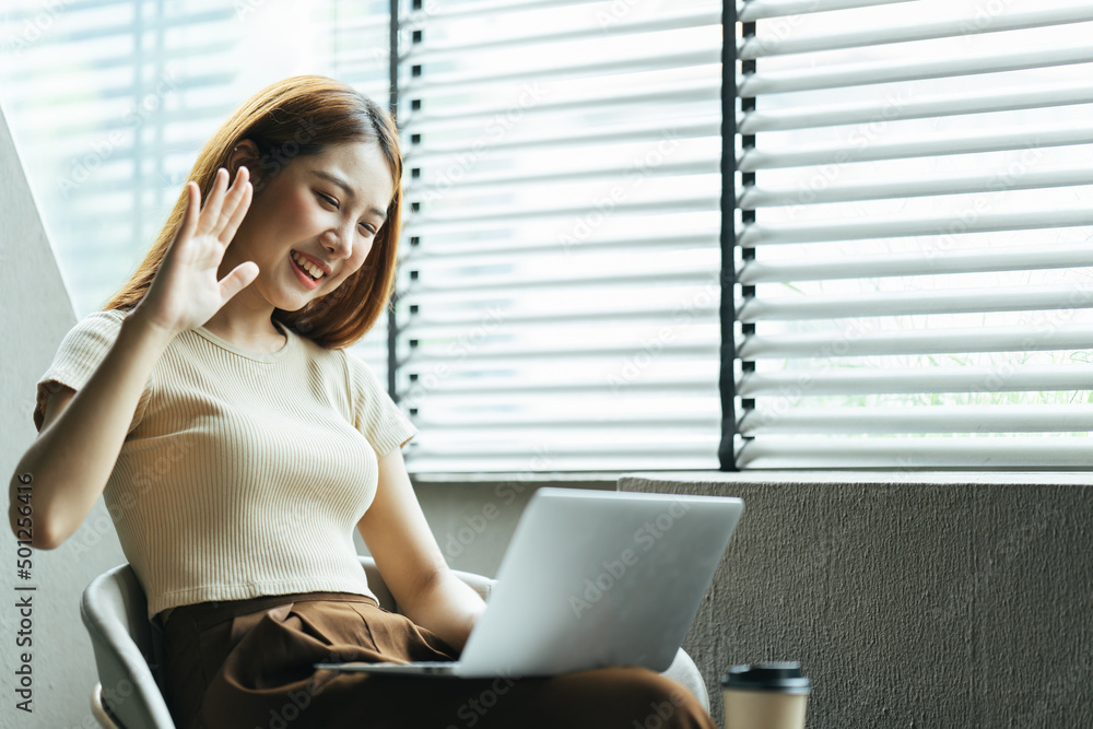 一名亚洲女子在家里的电脑上进行视频通话。一个微笑的女孩在网上和老师一起学习。