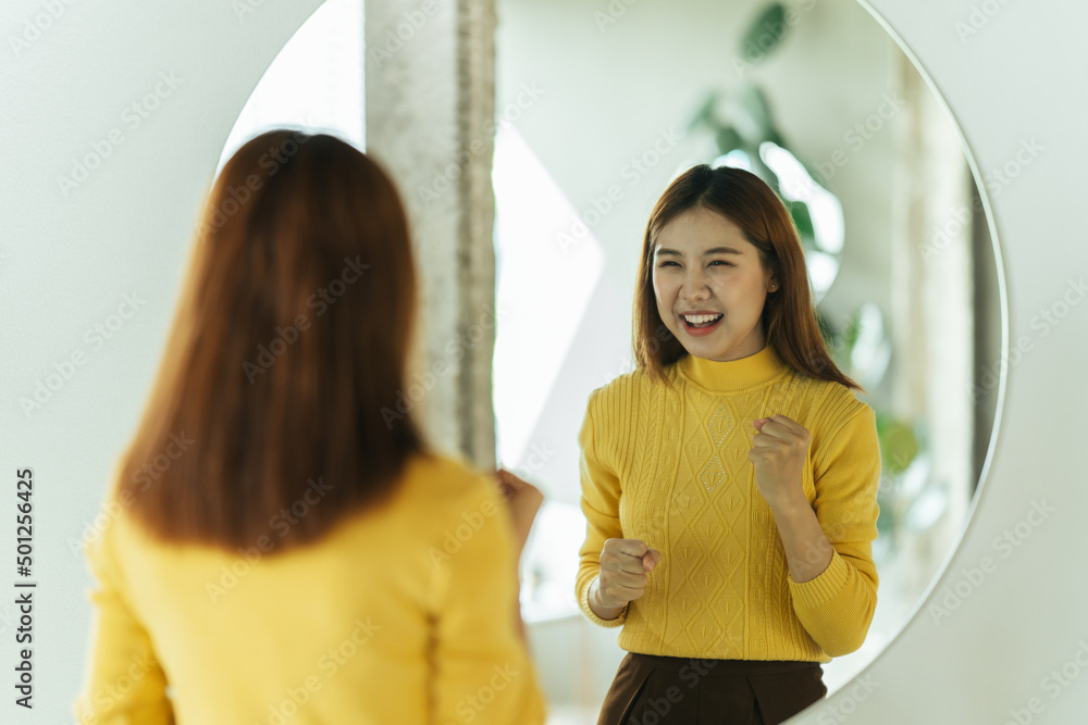 一位年轻的亚洲女性通过镜子与自己交谈，以建立自信并赋予自己权力