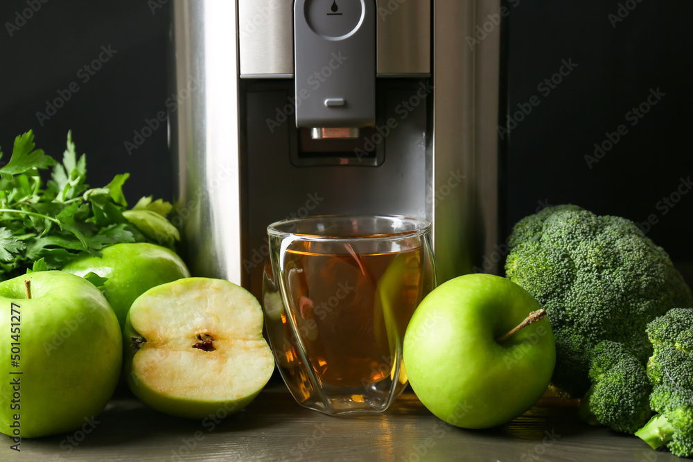 New modern juicer and glass of fresh juice on table