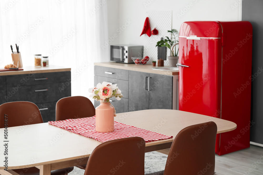 Vase with flowers on dining table in modern kitchen