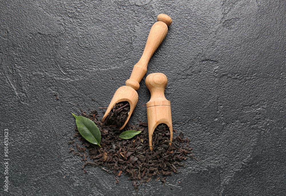 Scoops with dry tea leaves on dark background, top view