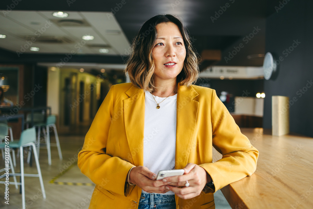 Pensive businesswoman holding a smartphone in an office