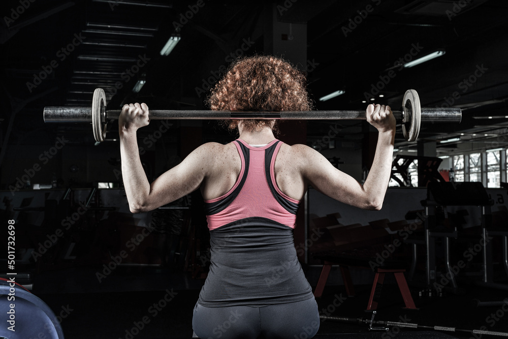 Woman bodybuilder engaged with a barbell in the gym