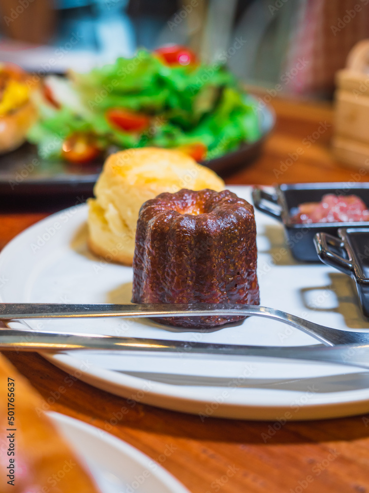 A canelé, french pastry on the white plate with blurred backgro