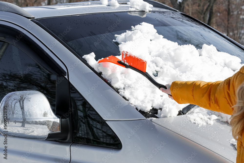 妇女在冬日清除车上的积雪