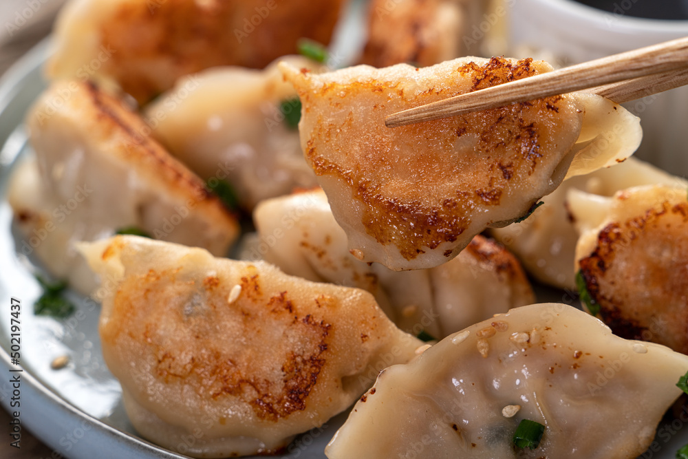 灰色桌子背景上放着酱油的锅里煎饺子饺子饺子。