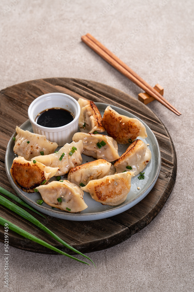 灰色桌子背景上放着酱油的锅里煎饺子饺子饺子。