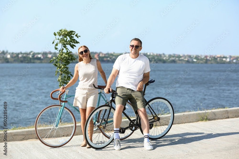 夏日，一对骑着自行车在河岸散步的成熟情侣