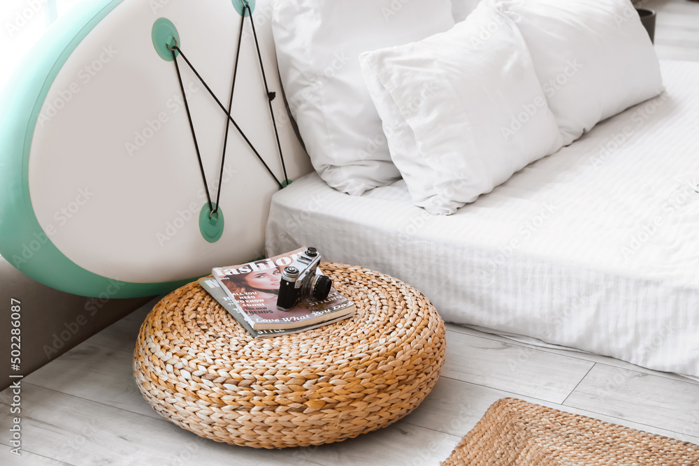 Sup board with big bed and wicker pouf in interior of room