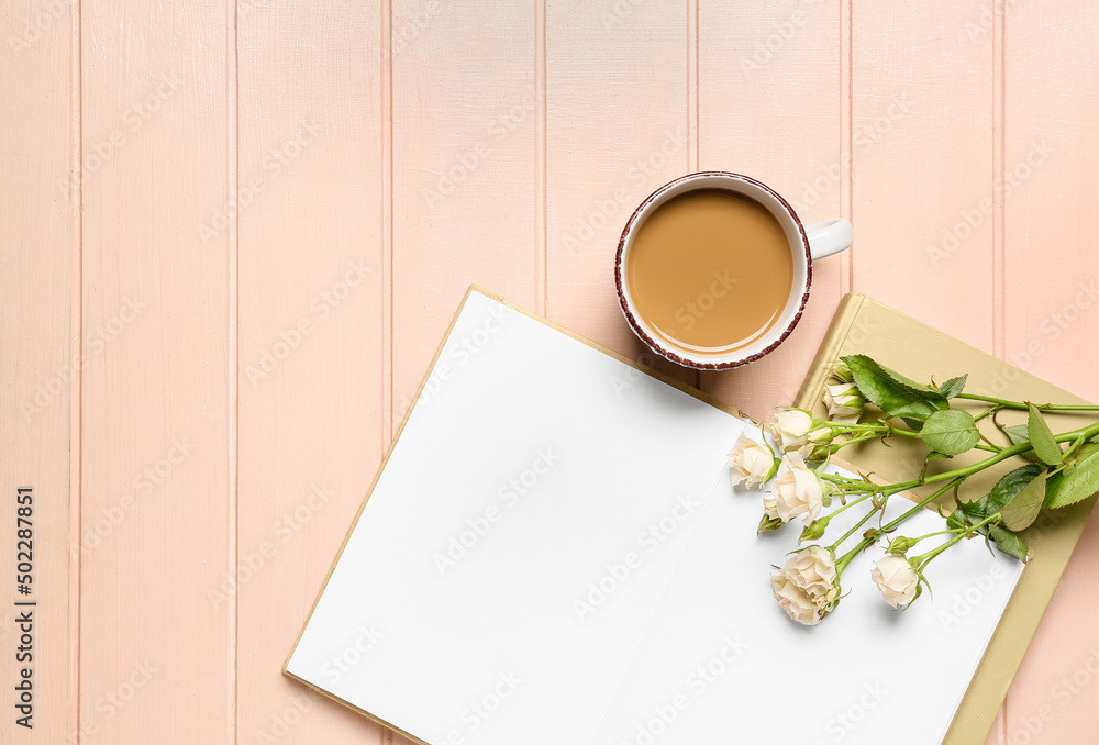 Opened book, flowers and cup of coffee on light wooden background