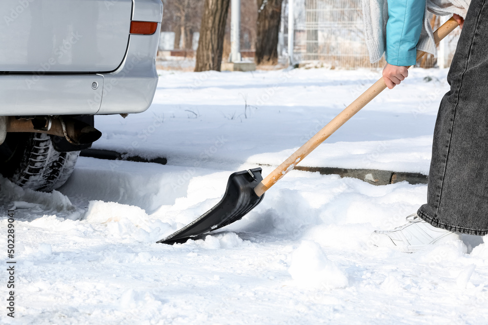 妇女在冬日清除汽车附近的积雪