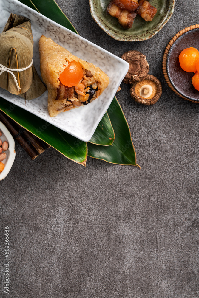 Zongzi, rice dumpling for Dragon Boat Festival on dark gray table background with ingredient.