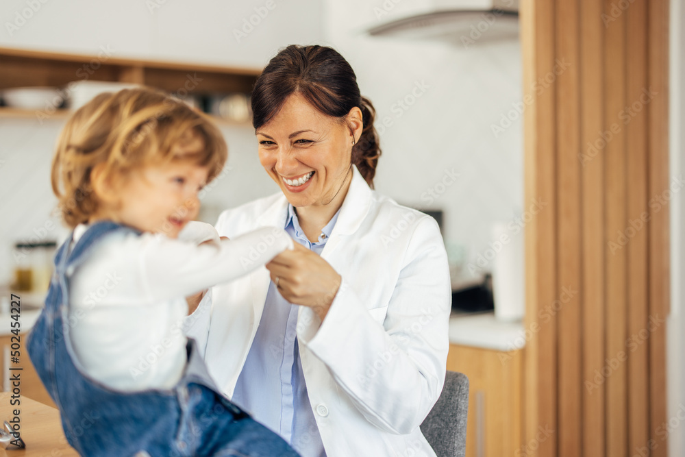 Cute toddler having a doctors visit at home, holding hands toge