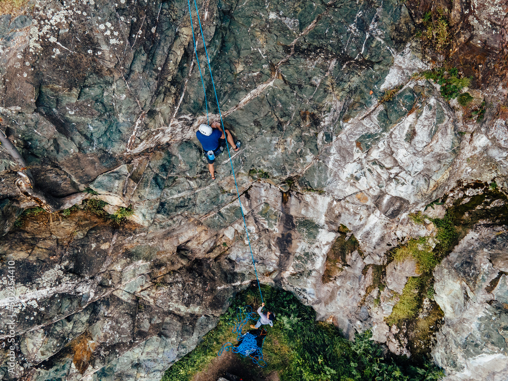 一名男子在登顶时为他的登山朋友提供安全保障的俯视图。