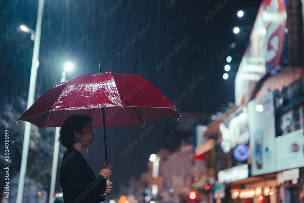 在雨中，一名亚洲妇女撑着一把伞。